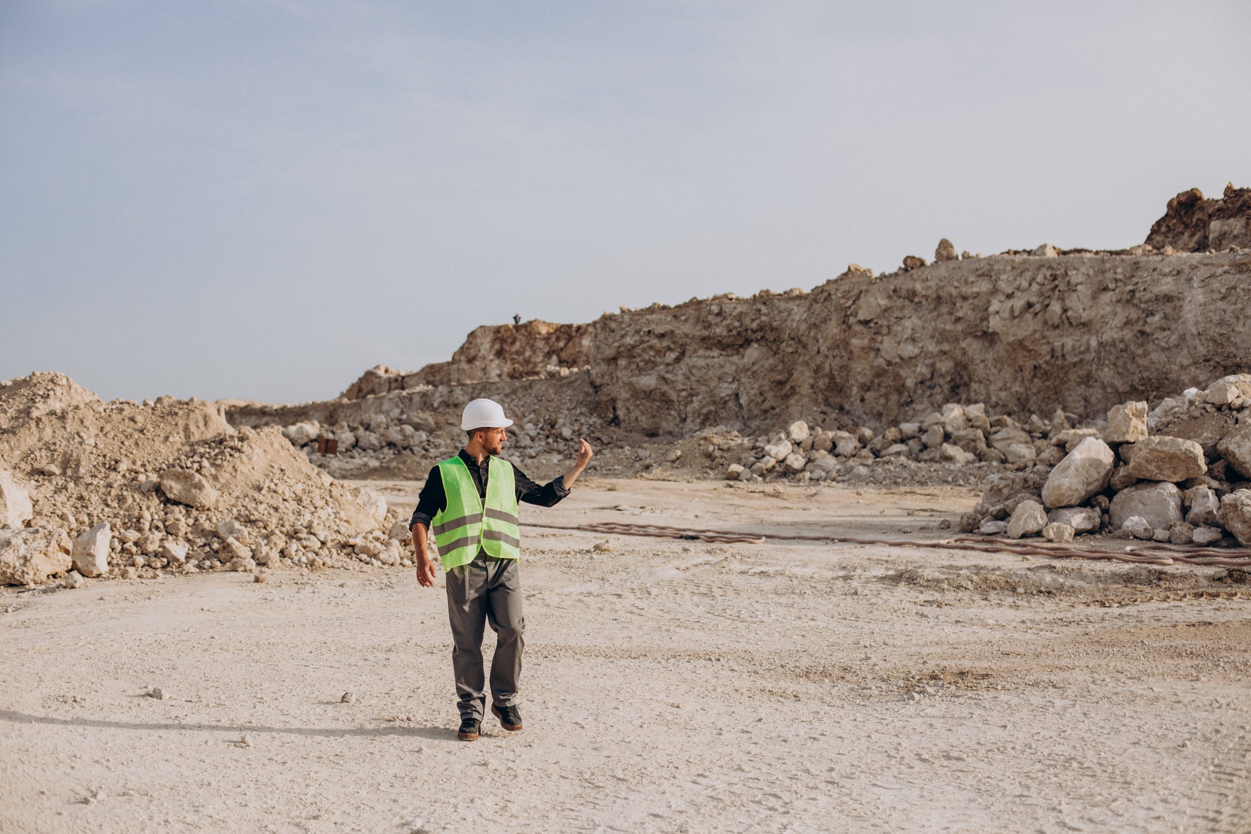 Worker in hardhat standing in sand quarry