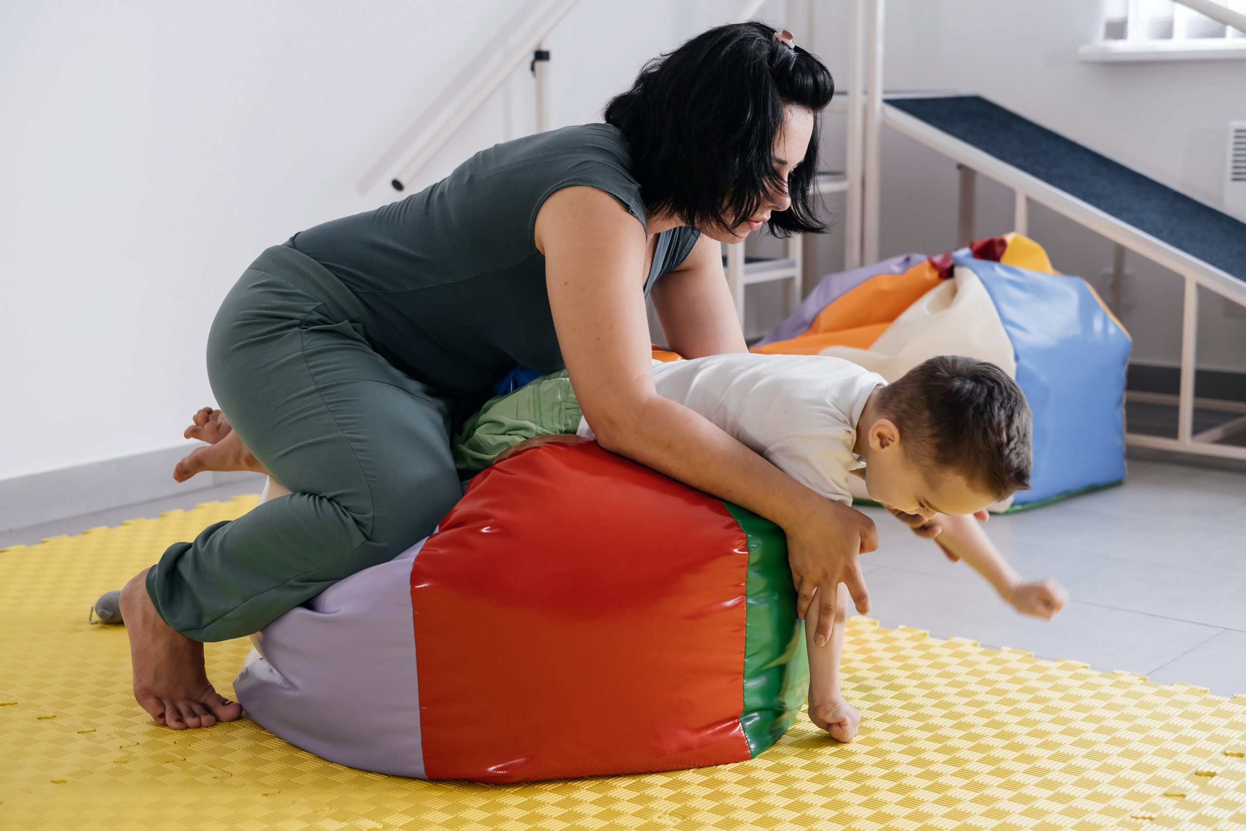 Therapist doing exercises on the mat with disabled child